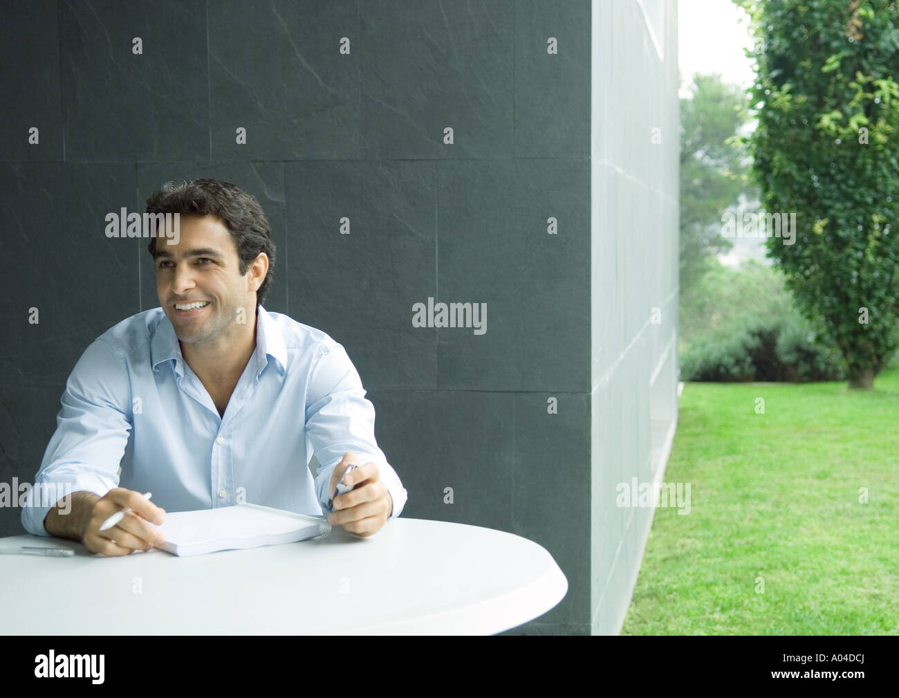 Man sitting at table outdoors, working Stock Photo