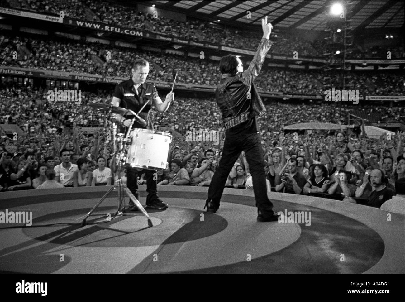 Larry and Bono  from U2 during the song Love and Peace live on The Vertigo Tour at  Twickenham Stadium Stock Photo