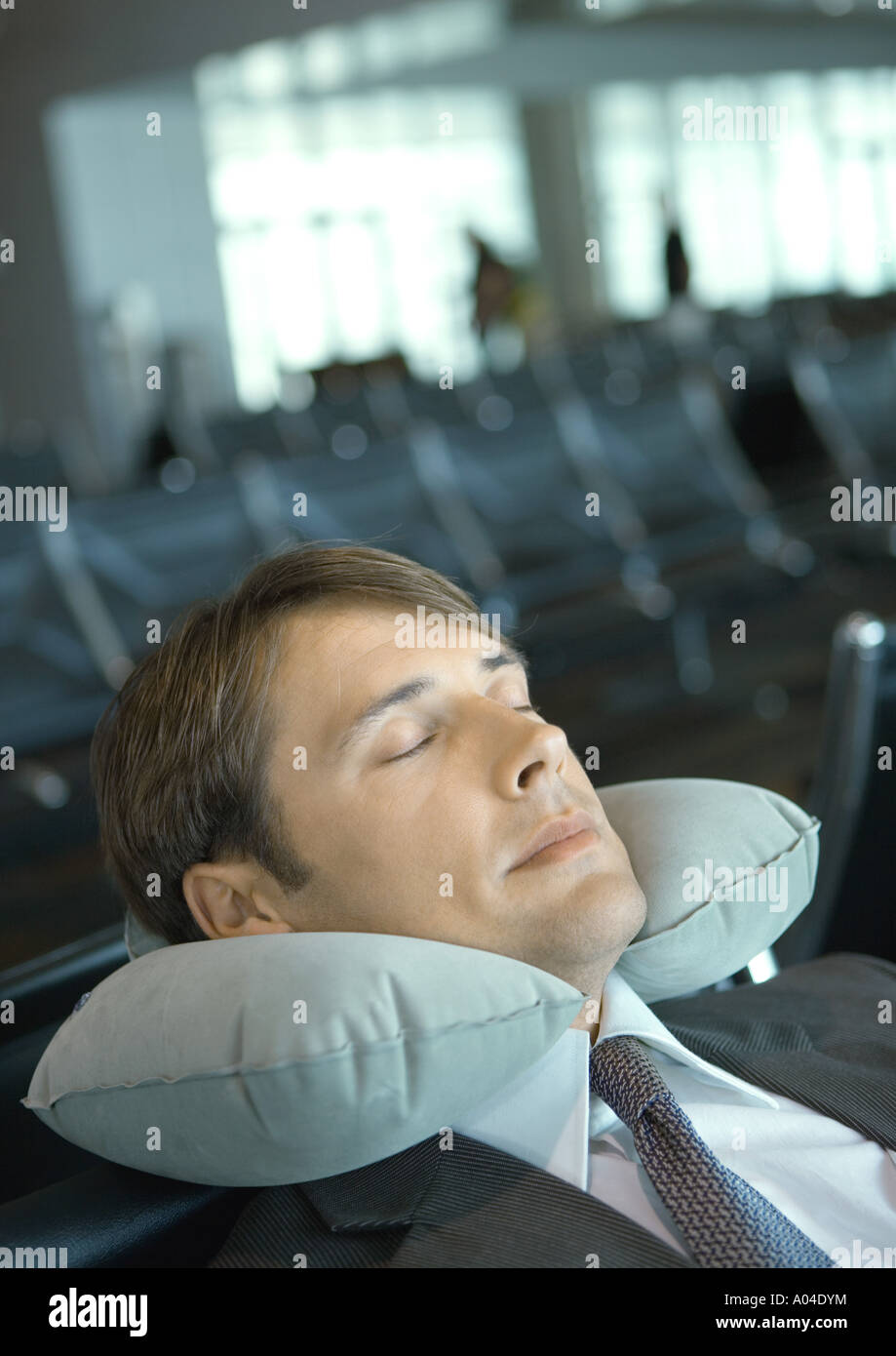 Man resting with neck pillow in airport lounge Stock Photo