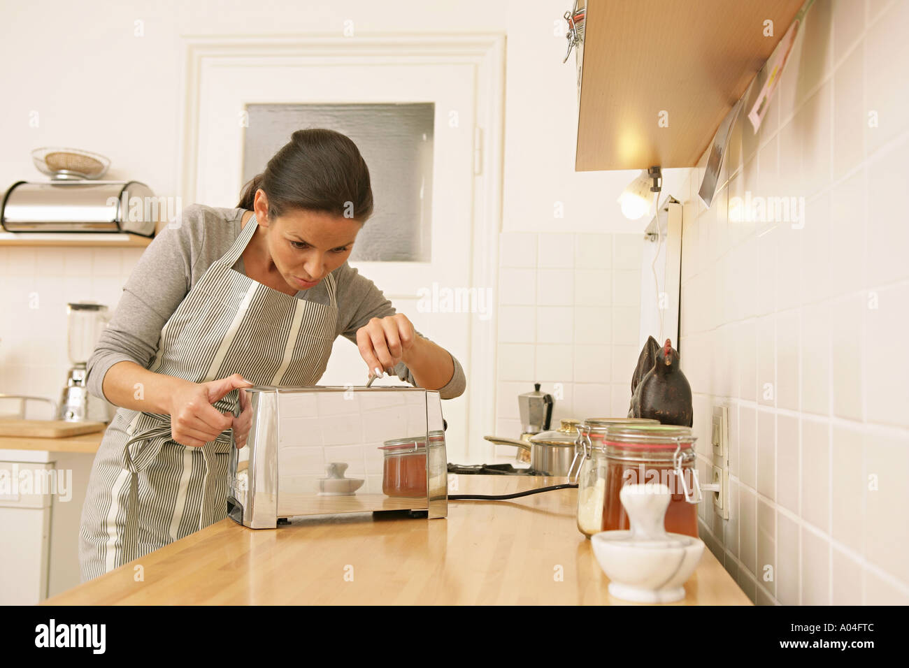 woman in kitchen dangerously sticking fork into toaster Stock Photo Alamy