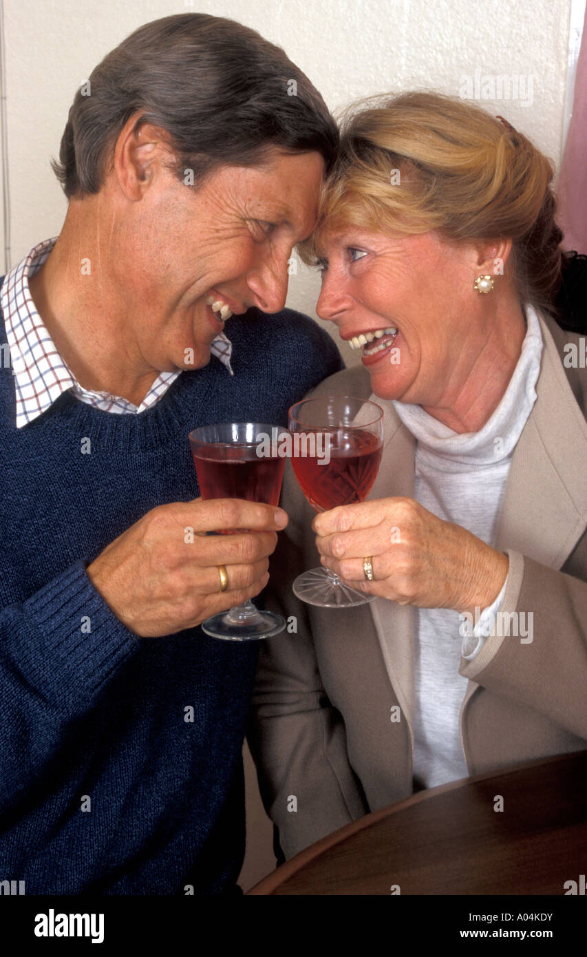 Happy romantic middle aged/mature couple congratulating each other with a glass of wine Stock Photo