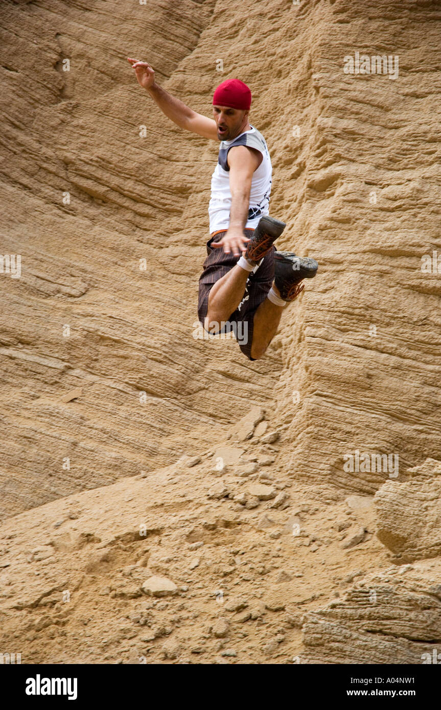 A marvellous pose from an exuberant free faller; background is of a beautifully defined beige coloured rock face Stock Photo