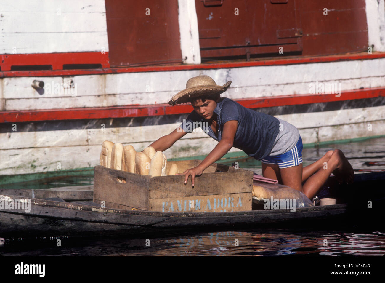 Manaus the river Amazon Brazil South America Teenage boy sells bread from a small boat to houseboats 1980S 1985 HOMER SYKES Stock Photo