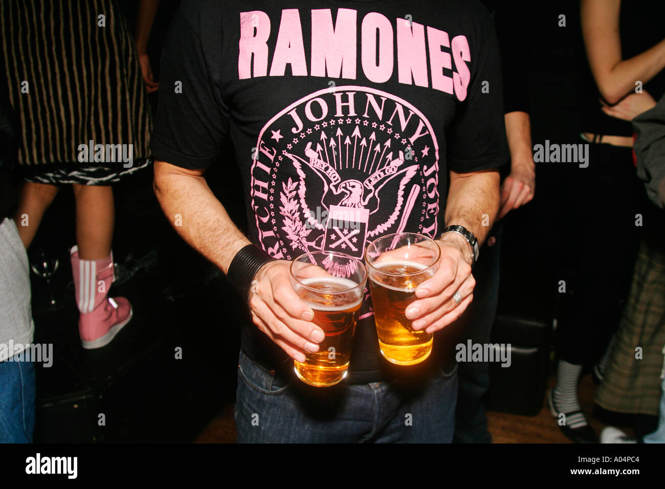 Close up of guy holding pints wearing a Ramones T Shirt at Golf Sale at The Lux Bar London Stock Photo