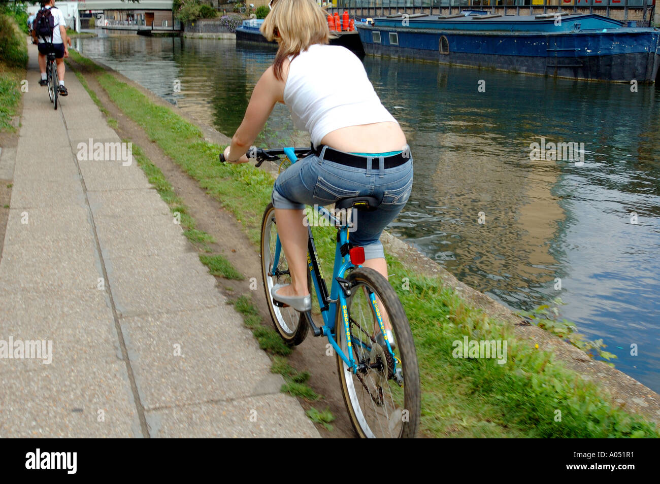 Rear side view of a female cyclist cycling on the path next to the canal, Regent's Canal, Islington, London Stock Photo