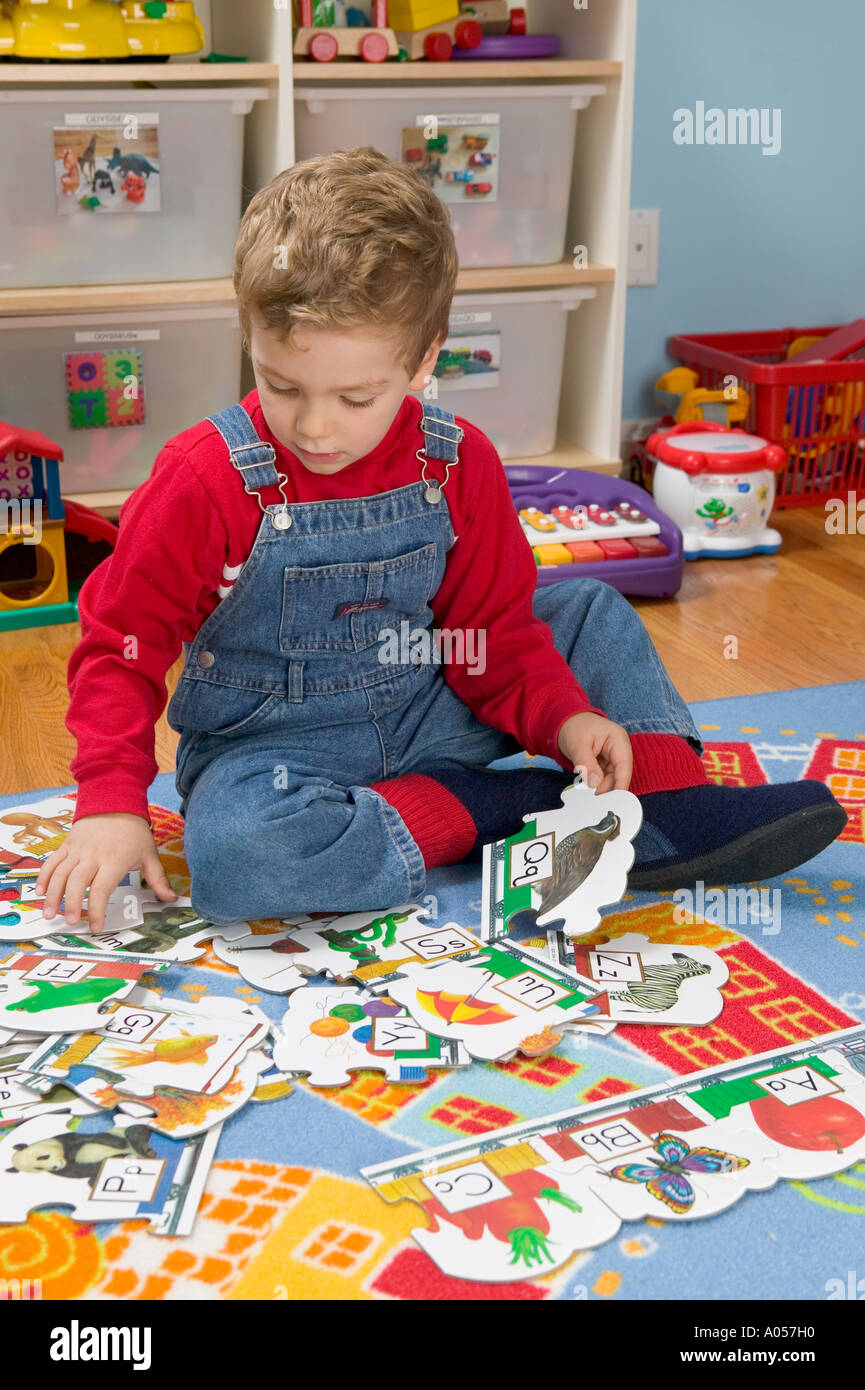 3 yr old boy tries to put together alphabet puzzle Stock Photo