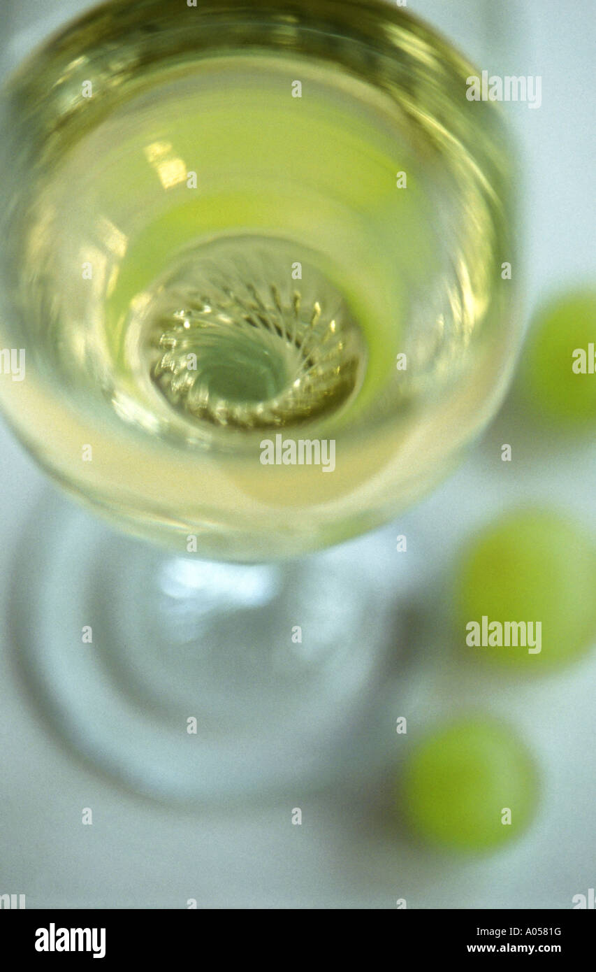 Abstract shot looking into a glass of white wine with three grapes at the base Stock Photo