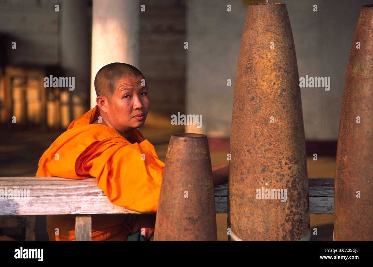 Monk next to US undetonated bombs. Phonsavan, Xieng Khuang, Laos. Stock Photo