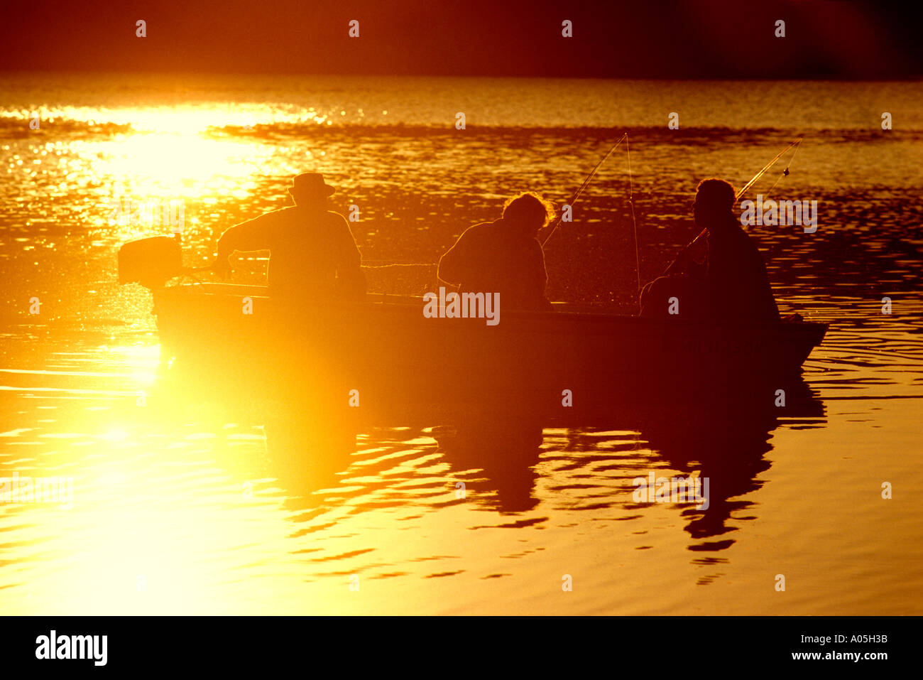 Silhouette of men sitting in a fishing boat on a lake at sunrise on ...