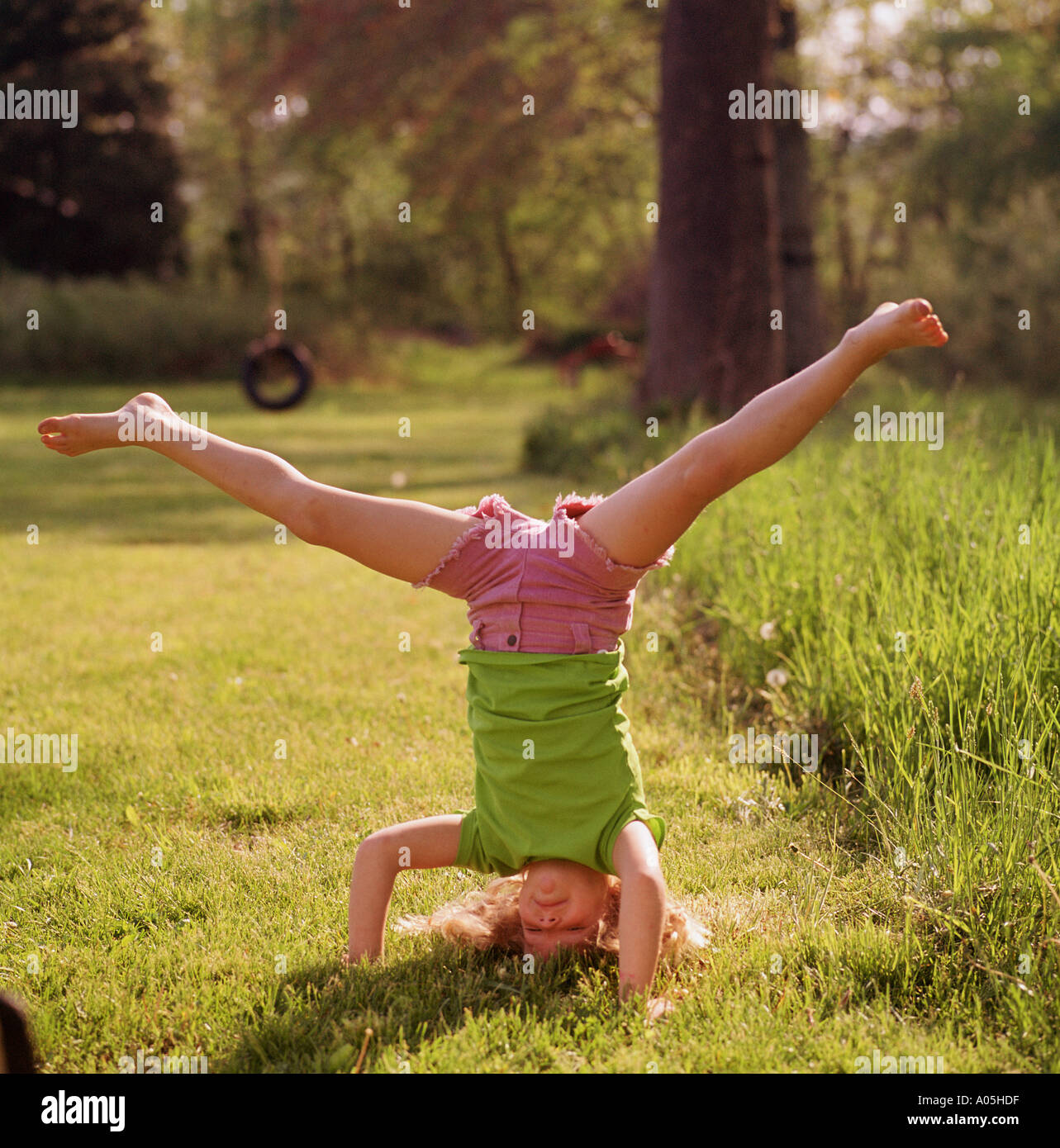 Young girl standing on her head and hands doing an upside down split