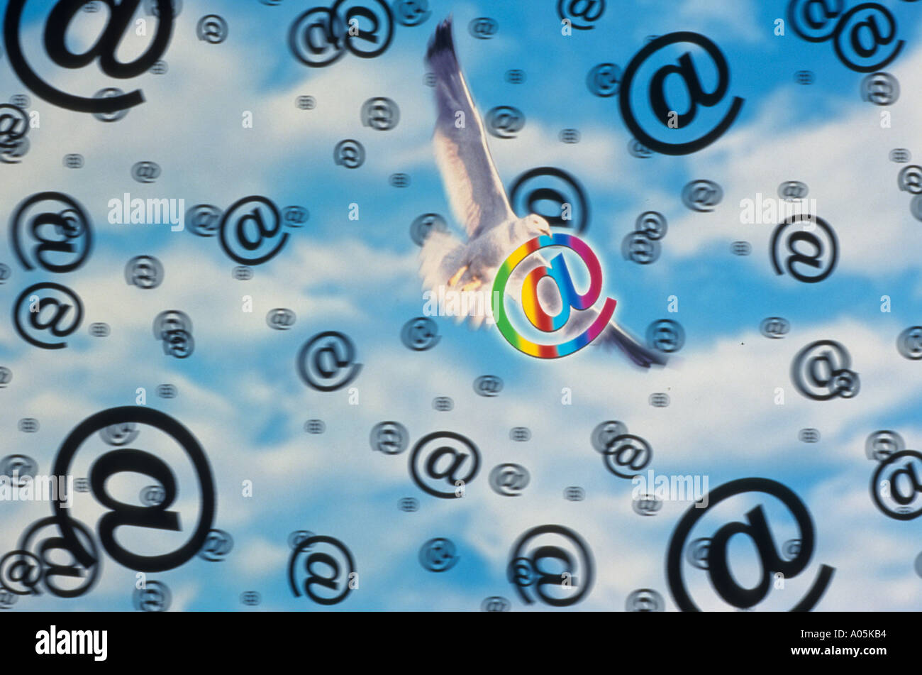 Conceptual illustration of a white dove flying amongst the clouds and the internet symbol denoting the at sign Stock Photo