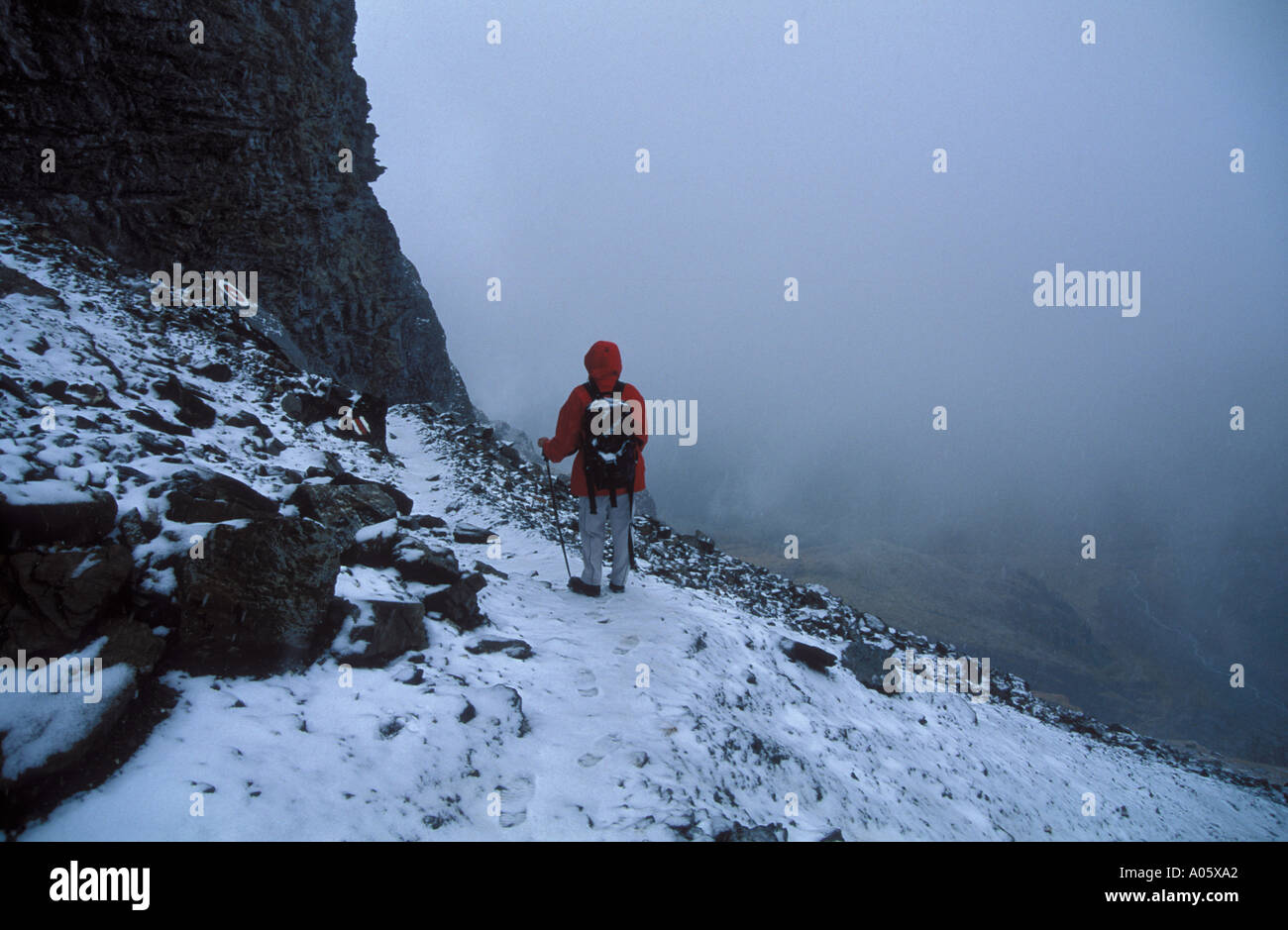 Hiker walking on alpine trail in fog and snwo Loetschenpass Bernese Alps below Gastern valley Switzerland Stock Photo