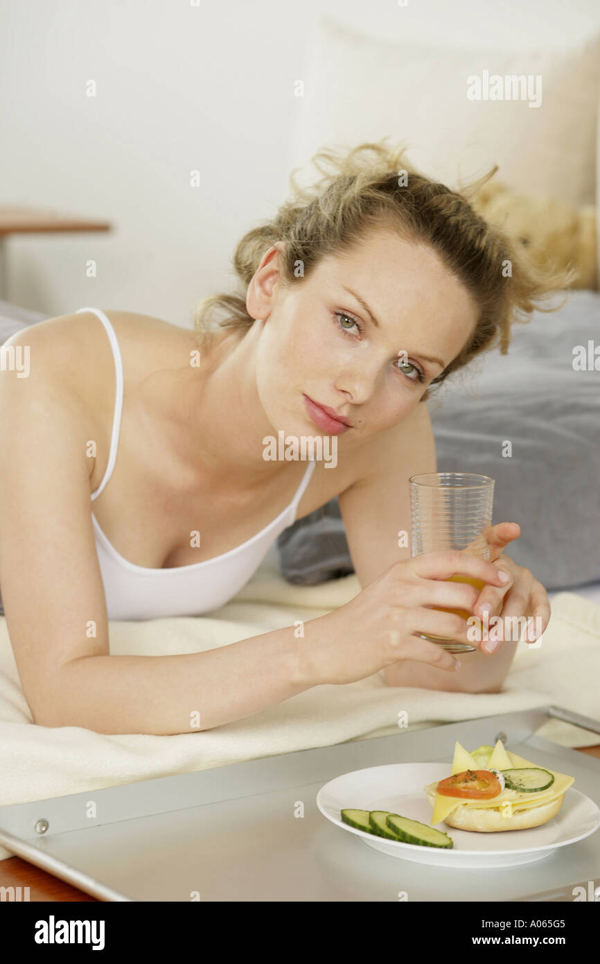 A young woman eats as she lies in her bed Stock Photo