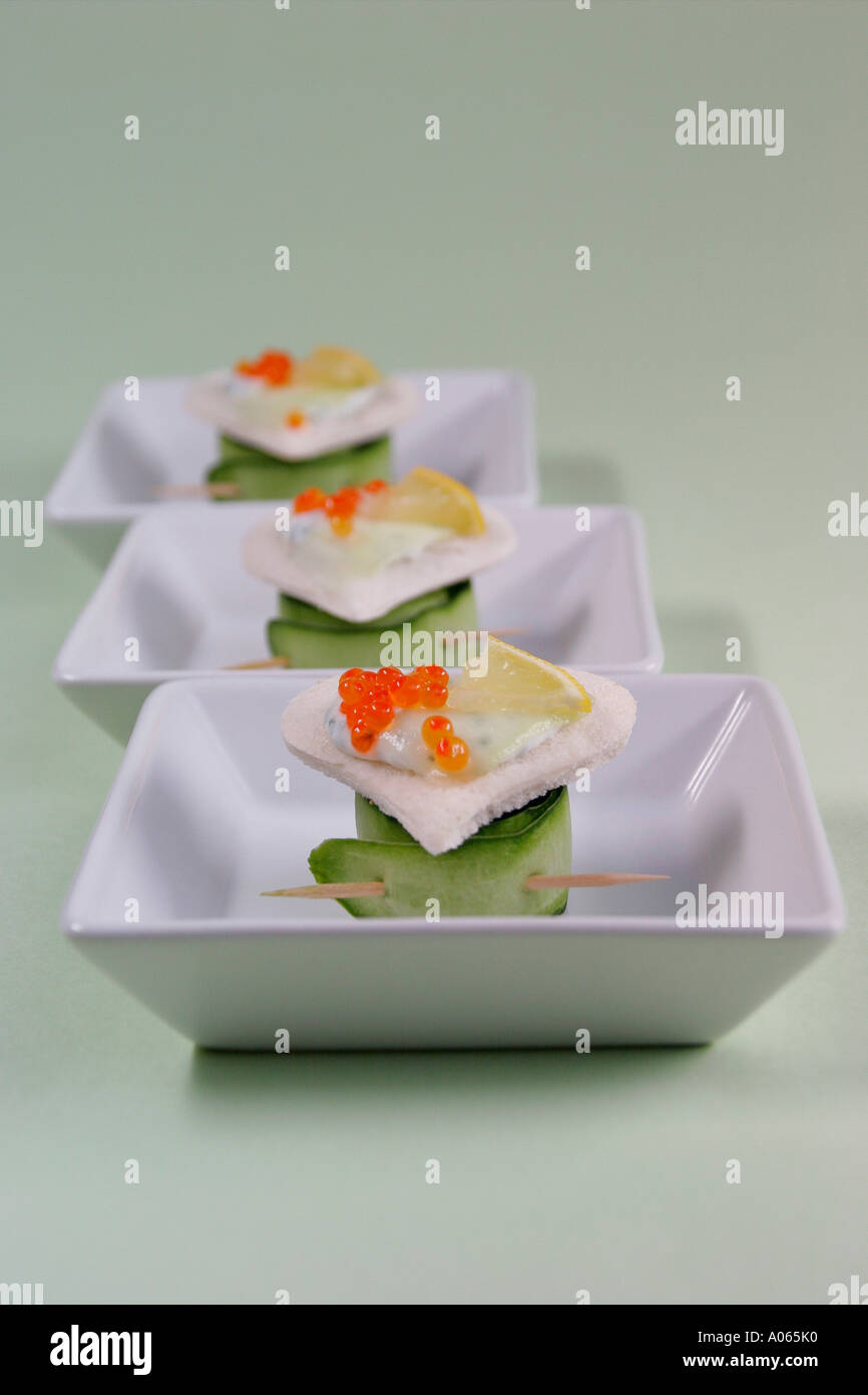 Cucumber rolls are placed below a heart shaped garnished foodstuff in three bowls Stock Photo