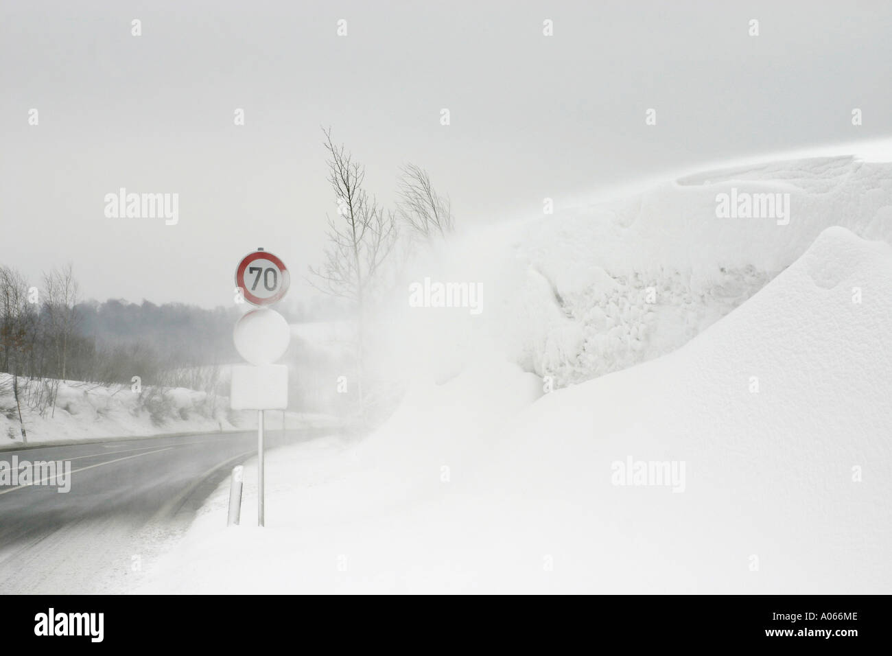 A glare of snow is seen near the road with a signboard at its side Stock Photo