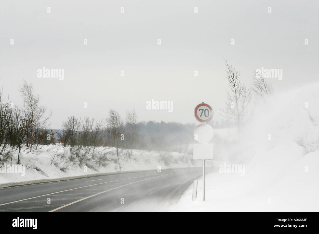 A glare of snow is seen near the road with a signboard at its side Stock Photo