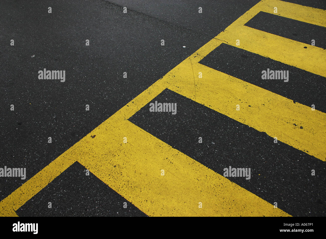 A section of a crosswalk with yellow stripes seen on the road Stock Photo