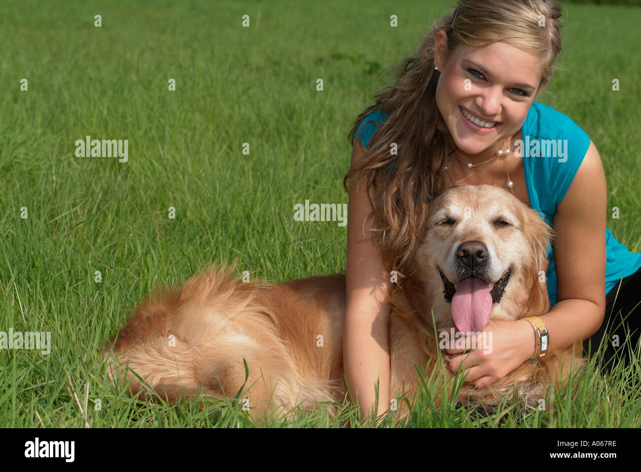 A blonde woman holding her pet dog smiles at the camera Stock Photo