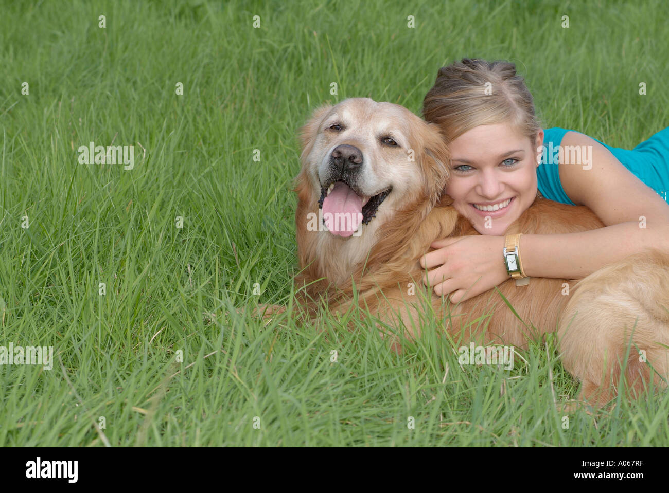 A blonde woman holding her pet dog smiles at the camera Stock Photo