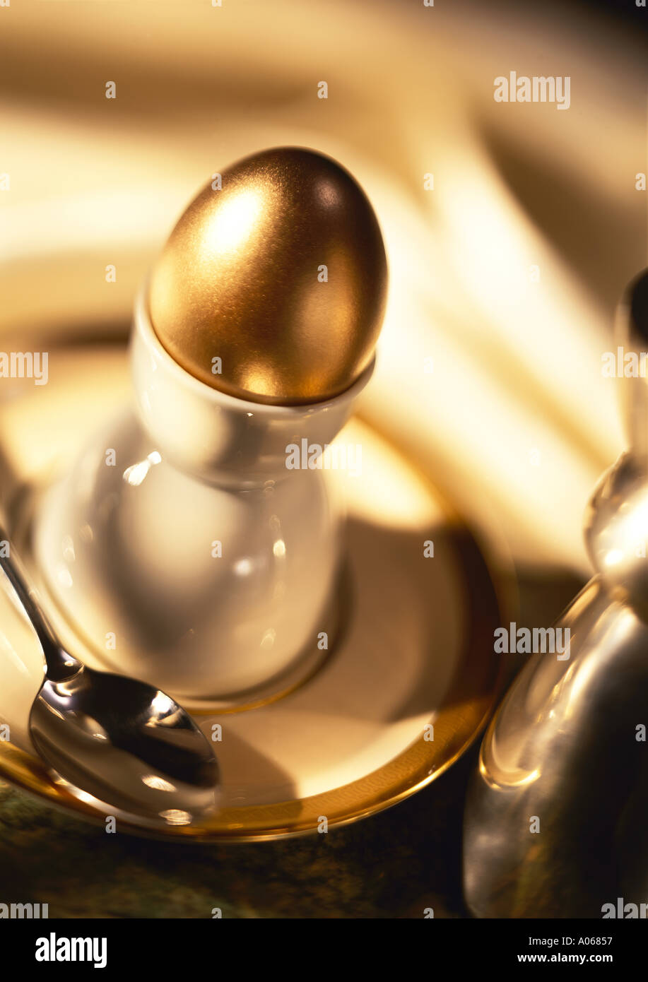Golden egg in egg cup Stock Photo