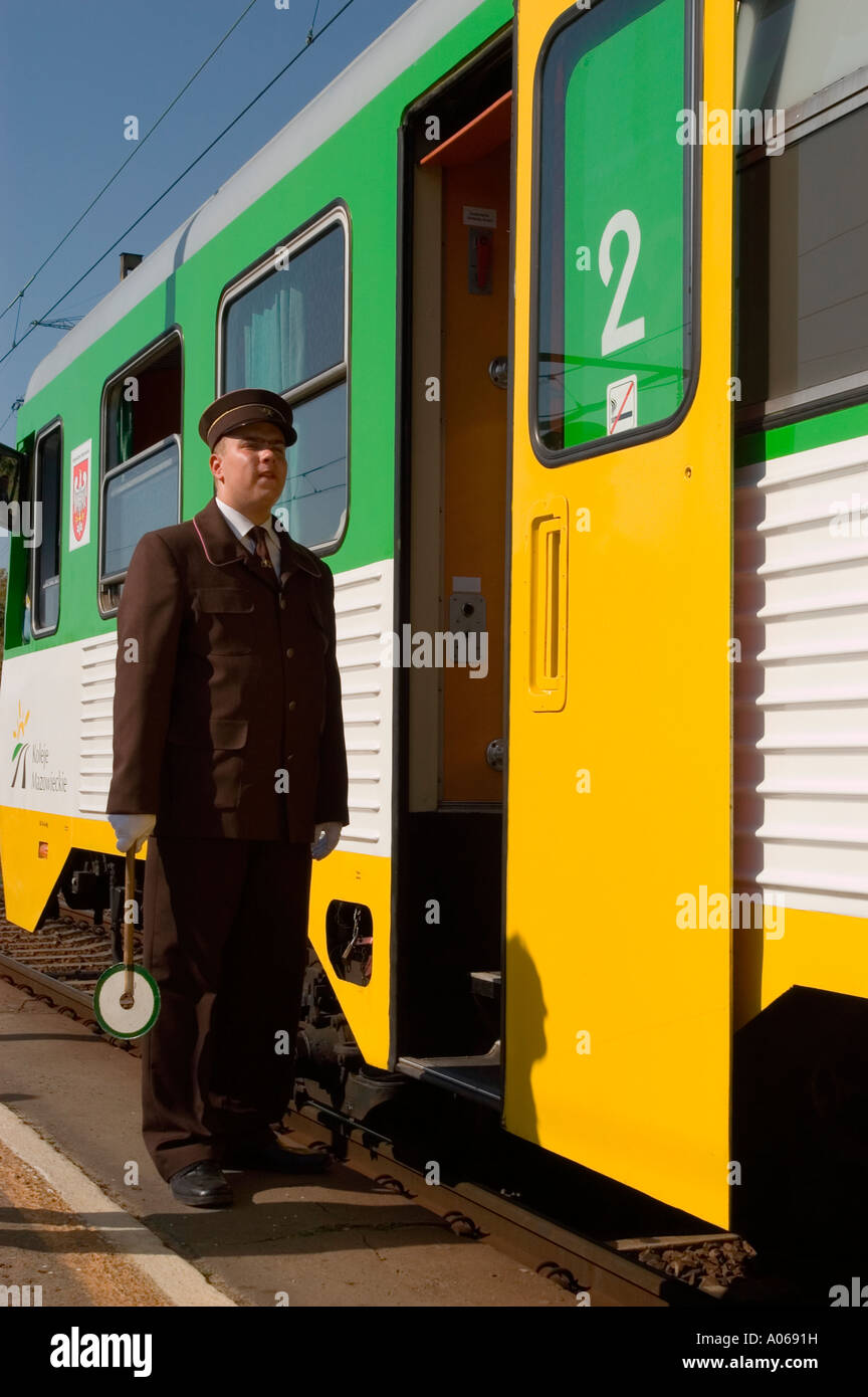 Train guard or conductor in brown uniform standing by a yellow and ...