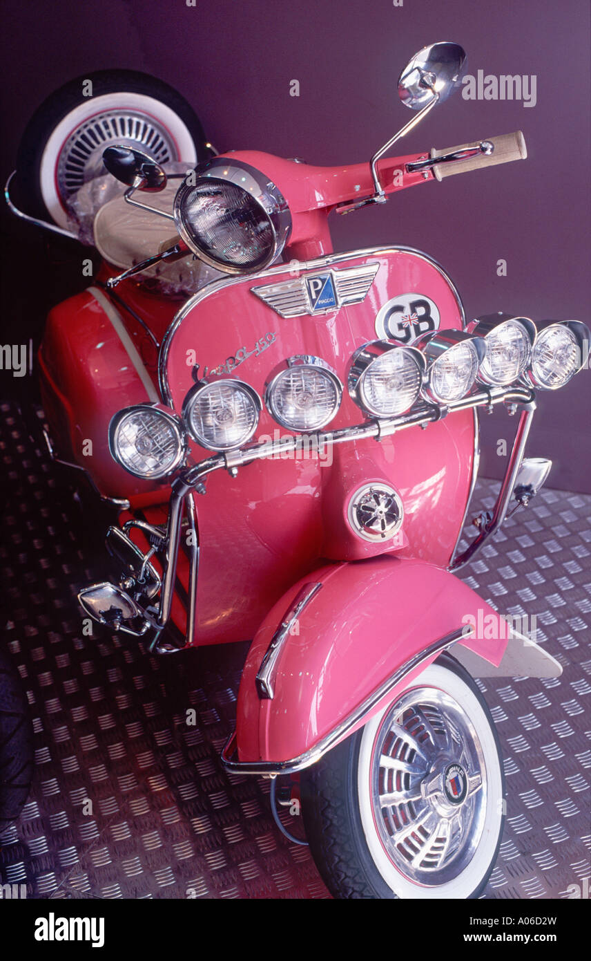 Hot pink Mod motor scooter (Vespa 150) sporting an array of chrome plated headlamps and rear view mirrors, London, England Stock Photo