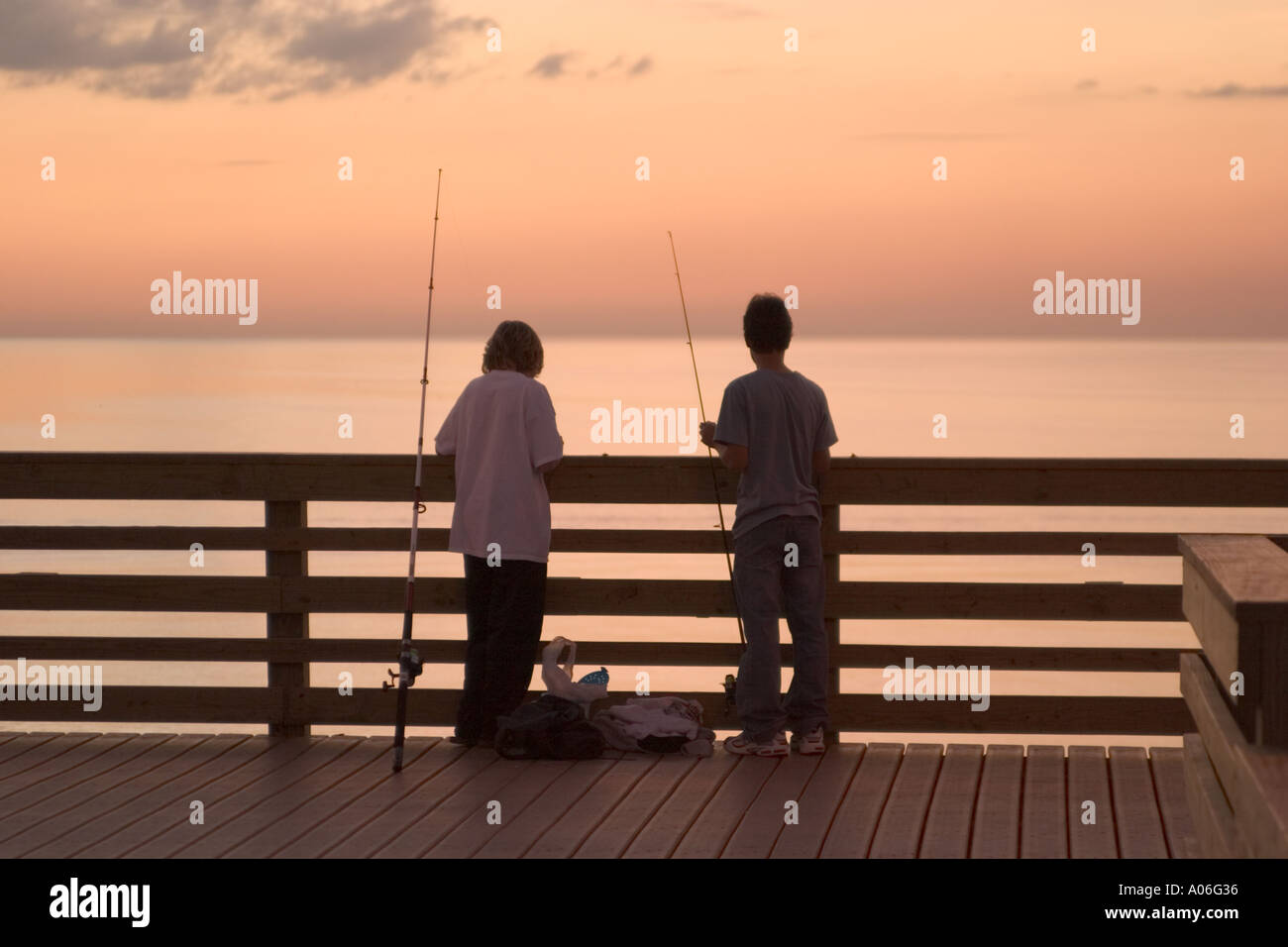 Silhouette of two boys fishing at sunset hi-res stock photography