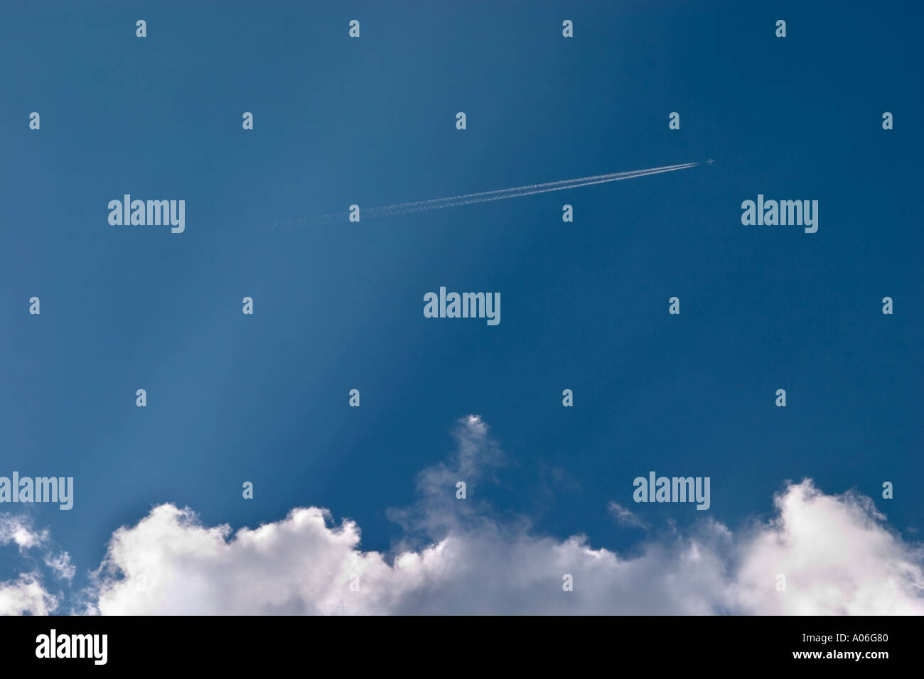 High flying plane in blue sky with big white clouds Stock Photo - Alamy