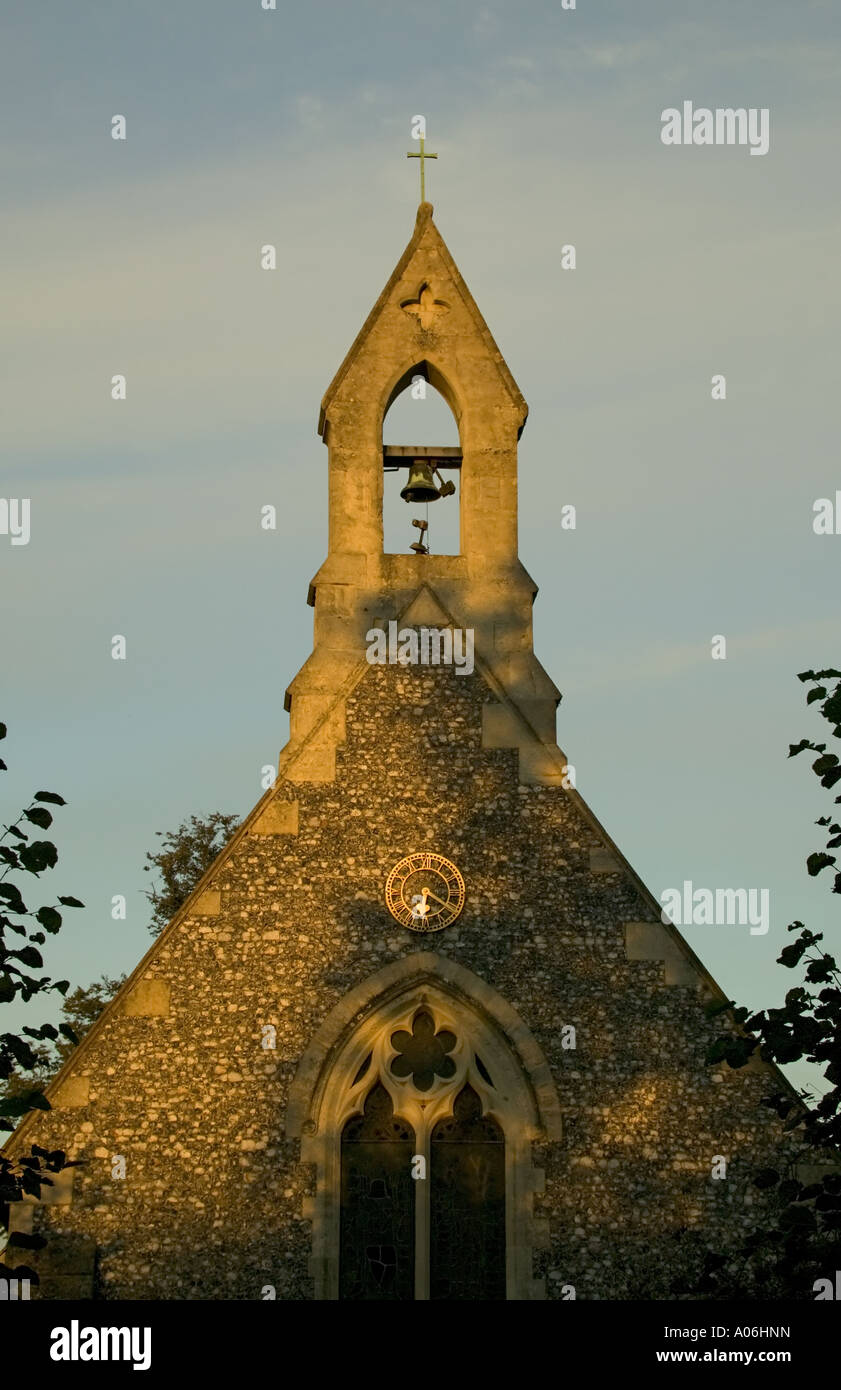 Church spire with bell tower in evening light against blue sky in Cookham Dean Stock Photo