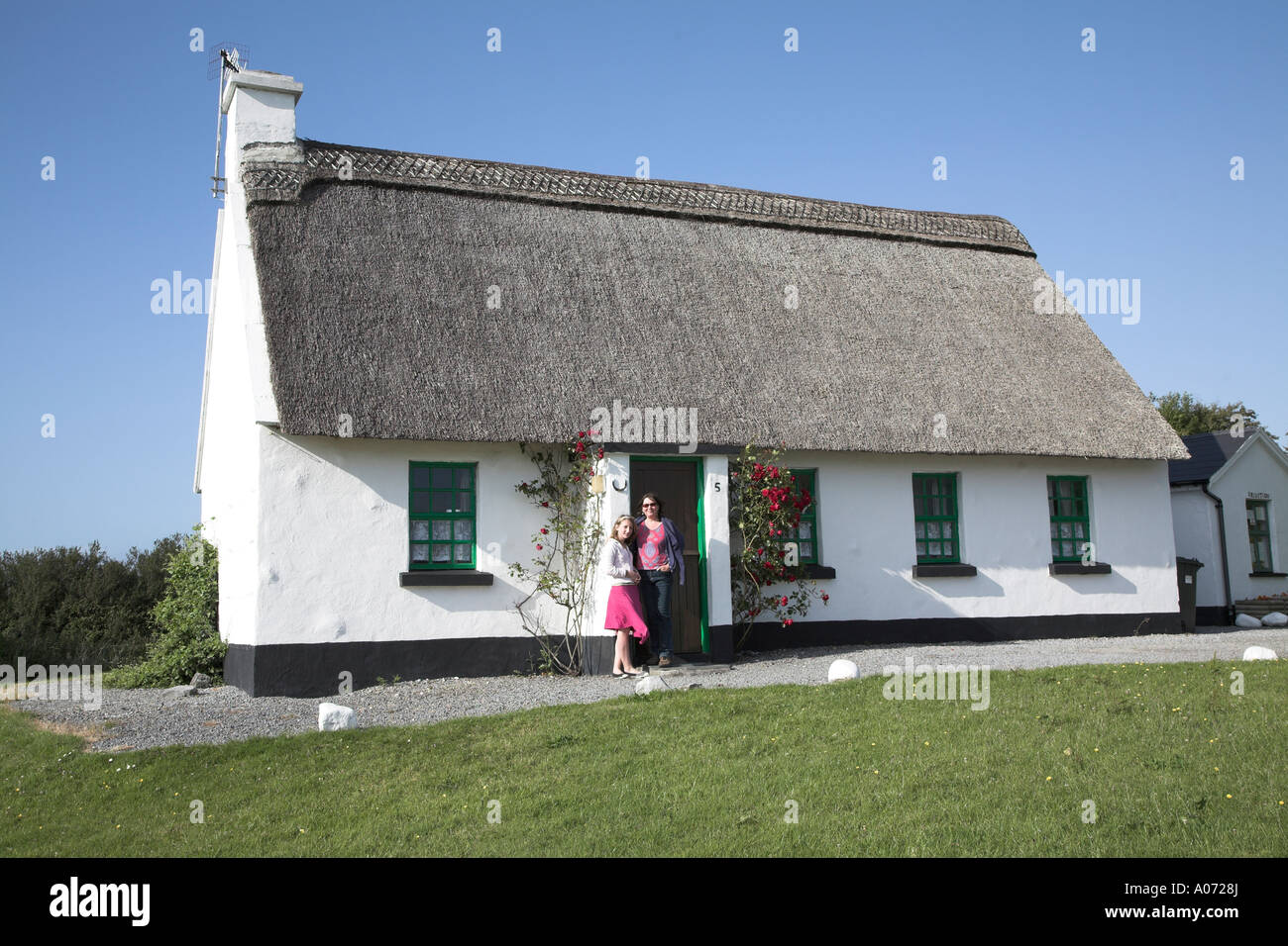 Woman And Girl Standing By A Thatched And Whitewashed Holiday