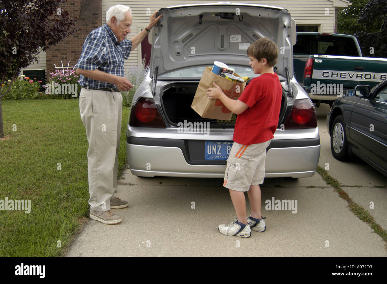 5th Grade Boy Helps Older Man Bring Groceries From Car 5 Stock Photo