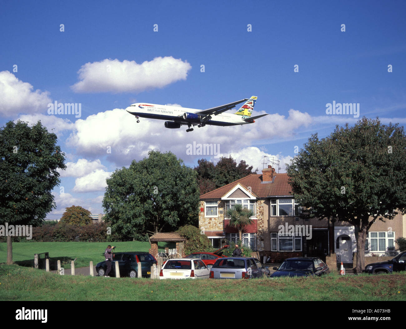 London Airport perimeter British Airways low flying passenger jet approaches runway above residential housing Stock Photo