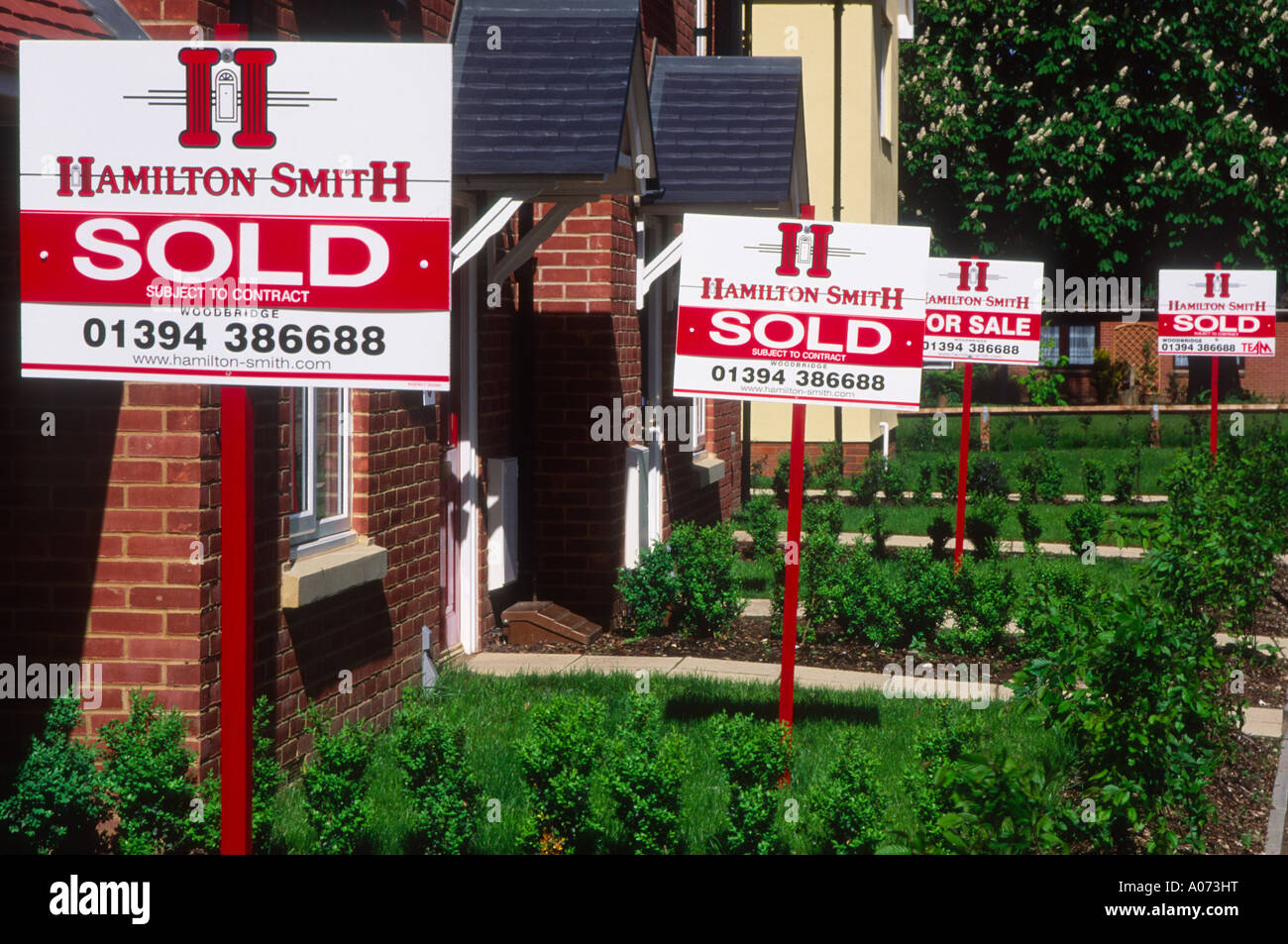 Property market estate agent signs saying Sold outside new housing