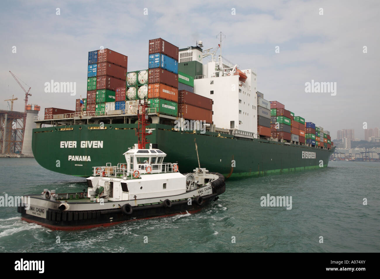 Tugboats manoevering around an ocean going containership at kwai chung container port in hong kong sar china fareast asia Stock Photo