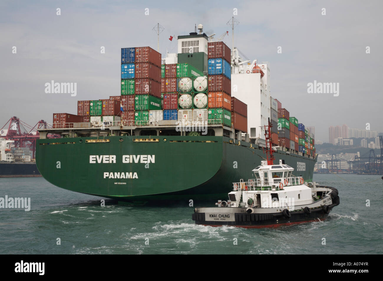 Tugboats manoevering around an ocean going containership at kwai chung container port in hong kong sar china fareast asia Stock Photo