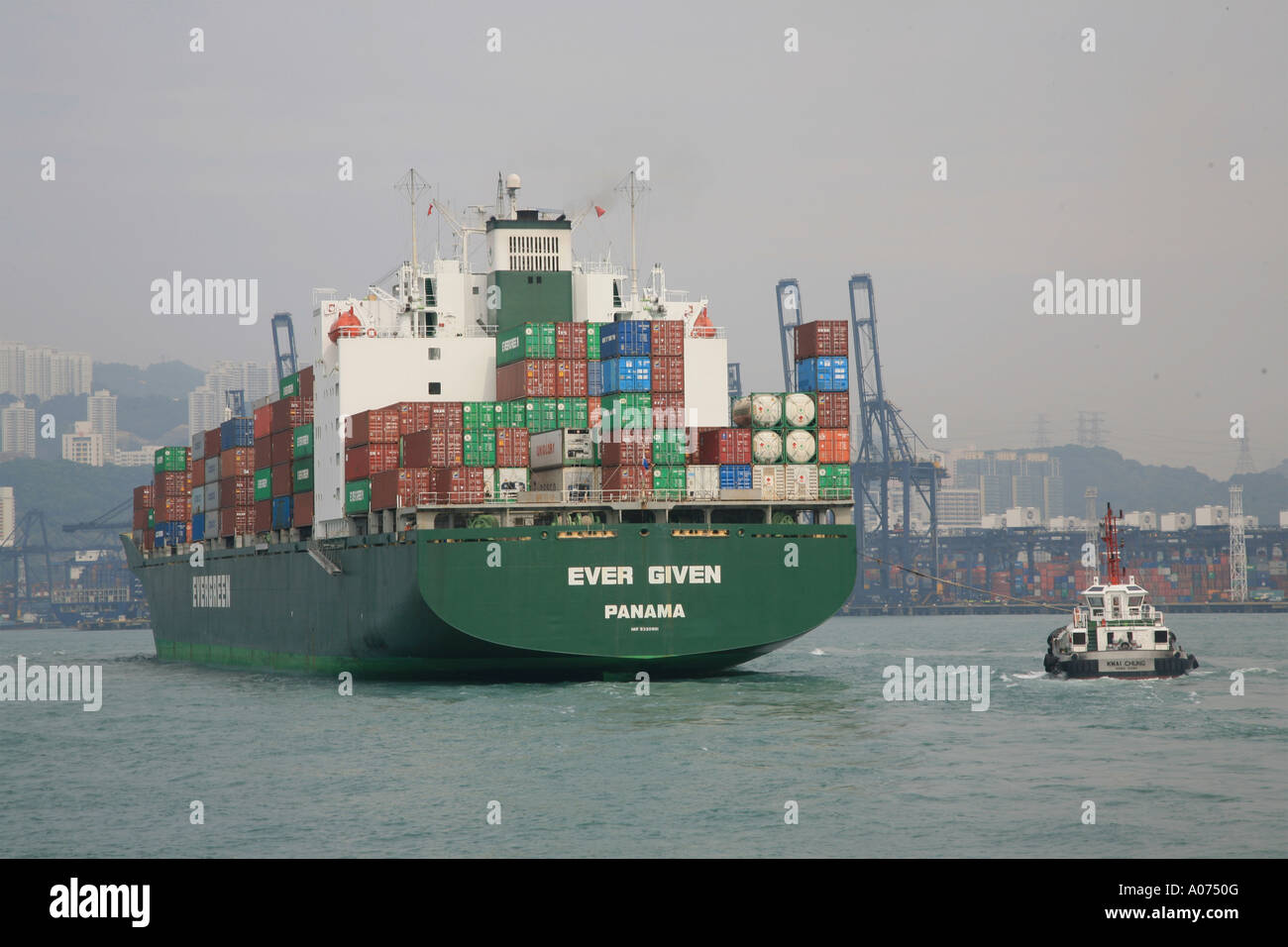 Tugboats manoevering around an ocean going containership at kwai chung container port in hong kong sar china fareast asia Stock Photo