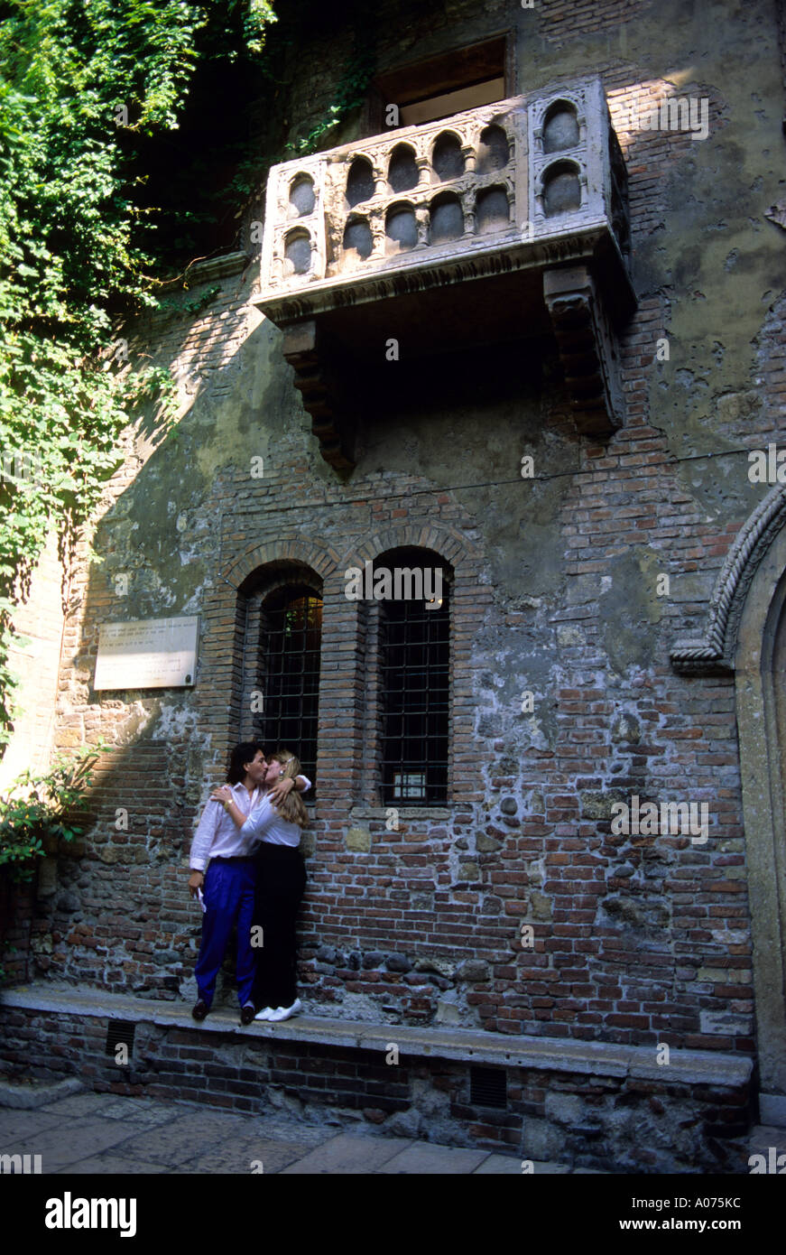 An Italian couple kissing below the balcony of Juliets house in Verona, Italy. Stock Photo