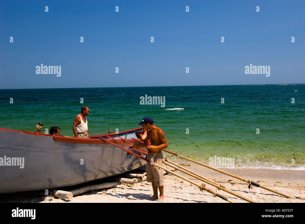 Fishermen painting boat on beach Vama Veche Black Sea Romania Europe Stock Photo
