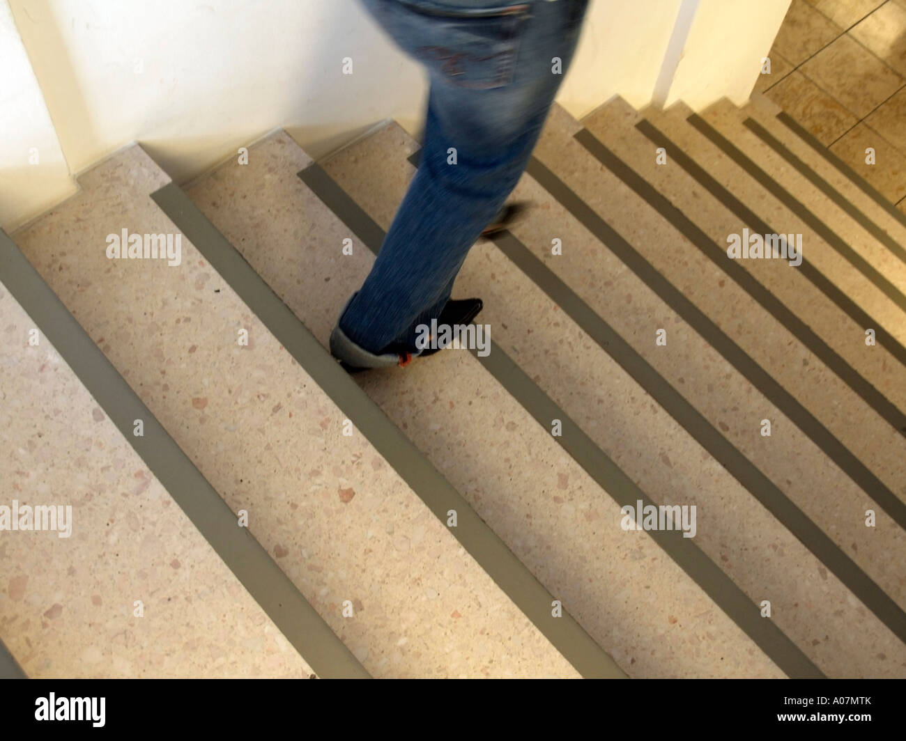 MR feet of a woman wearing sharp shoes and jeans in movement on stairs Stock Photo