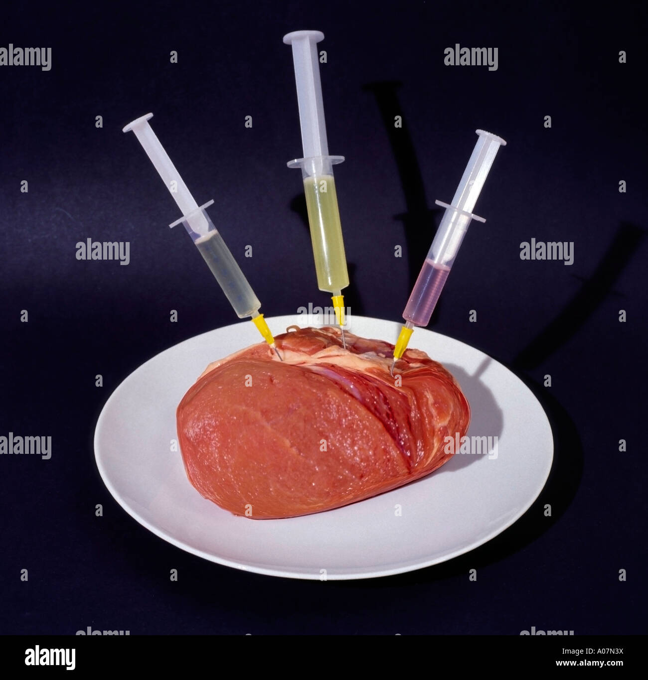 piece of pork with three syringes jabs shots Stock Photo
