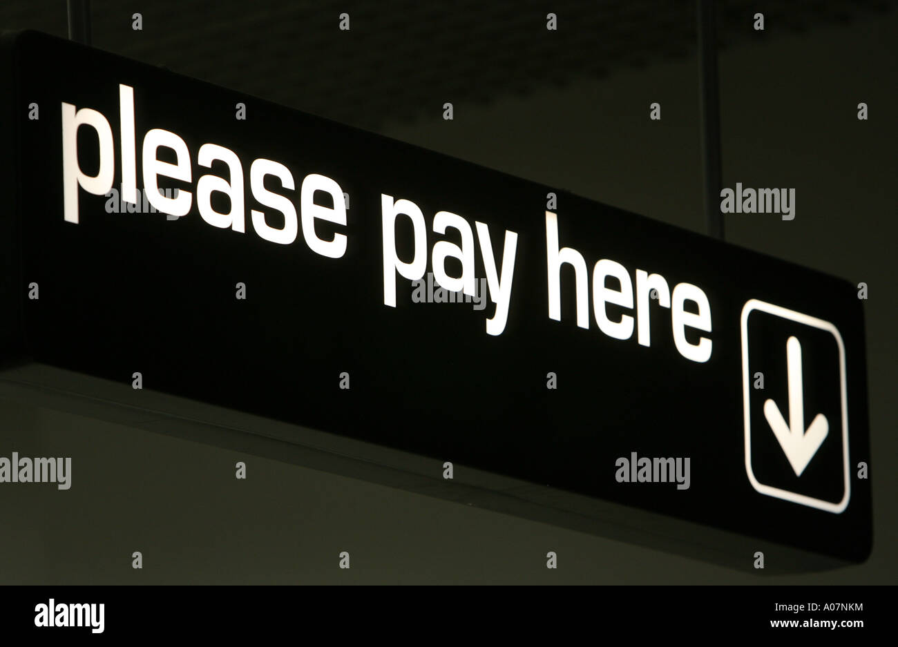 Illuminated sign saying Please Pay Here Stock Photo