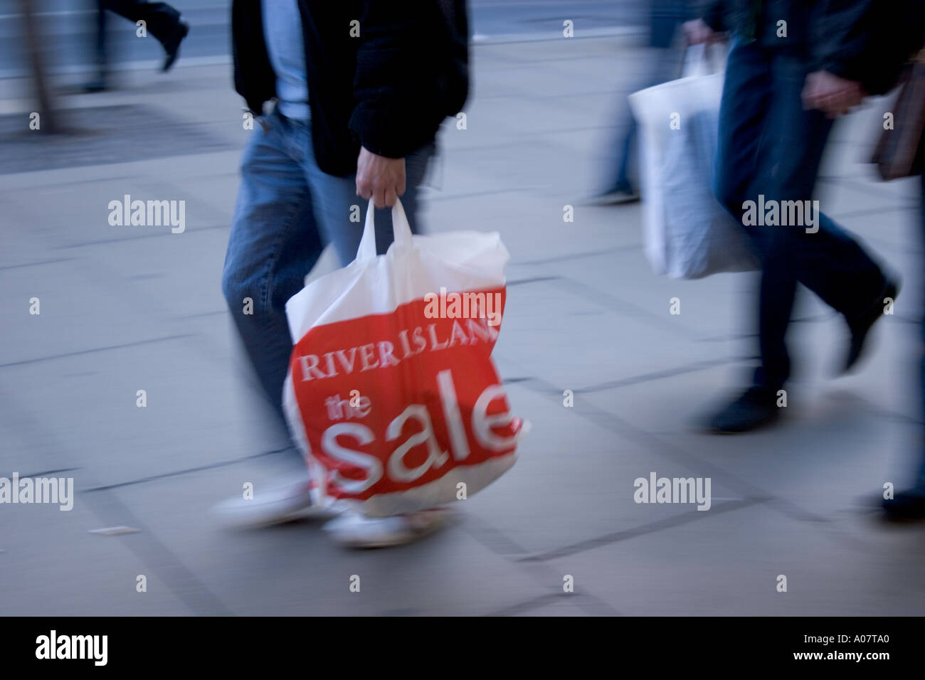 Shoppers in at January sales in Oxford Street London with River Island shopping bag Stock Photo