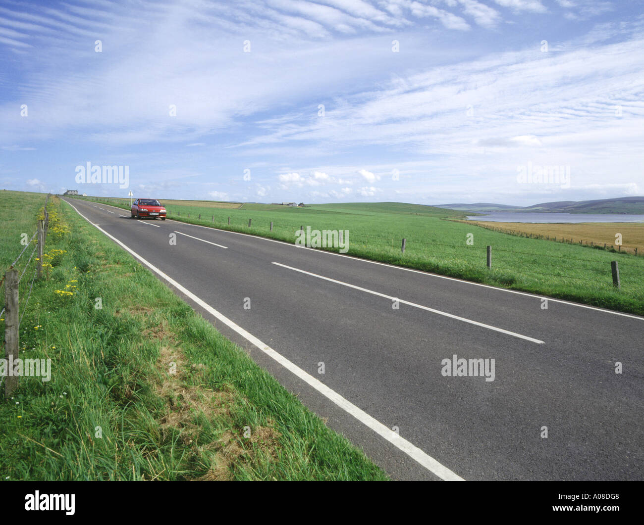 dh Loch of Stenness STROMNESS AREA ORKNEY Red car wide road green fields and loch countryside Stock Photo