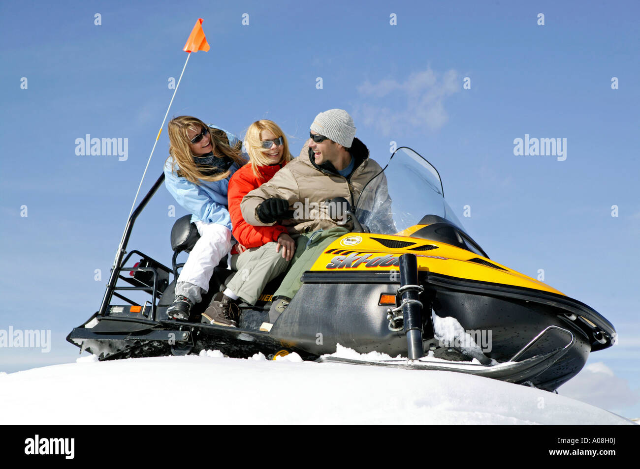 Mann und zwei Frauen unterwegs mit einem Snowmobil, Two Women and Man on Ski Scooter Winter Holiday Stock Photo