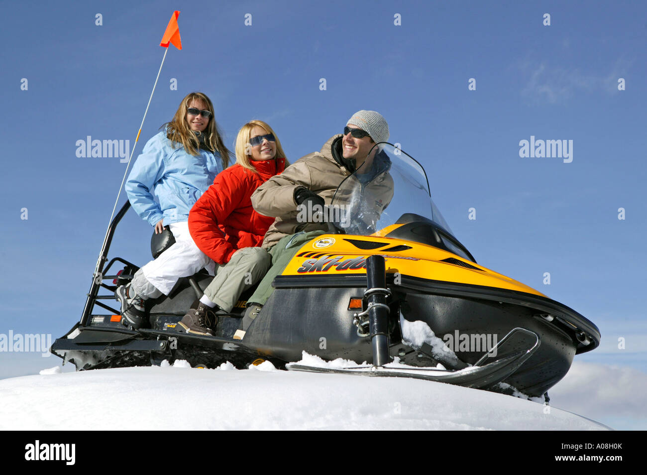 Mann und zwei Frauen unterwegs mit einem Snowmobil, Two Women and Man on Ski Scooter Winter Holiday Stock Photo