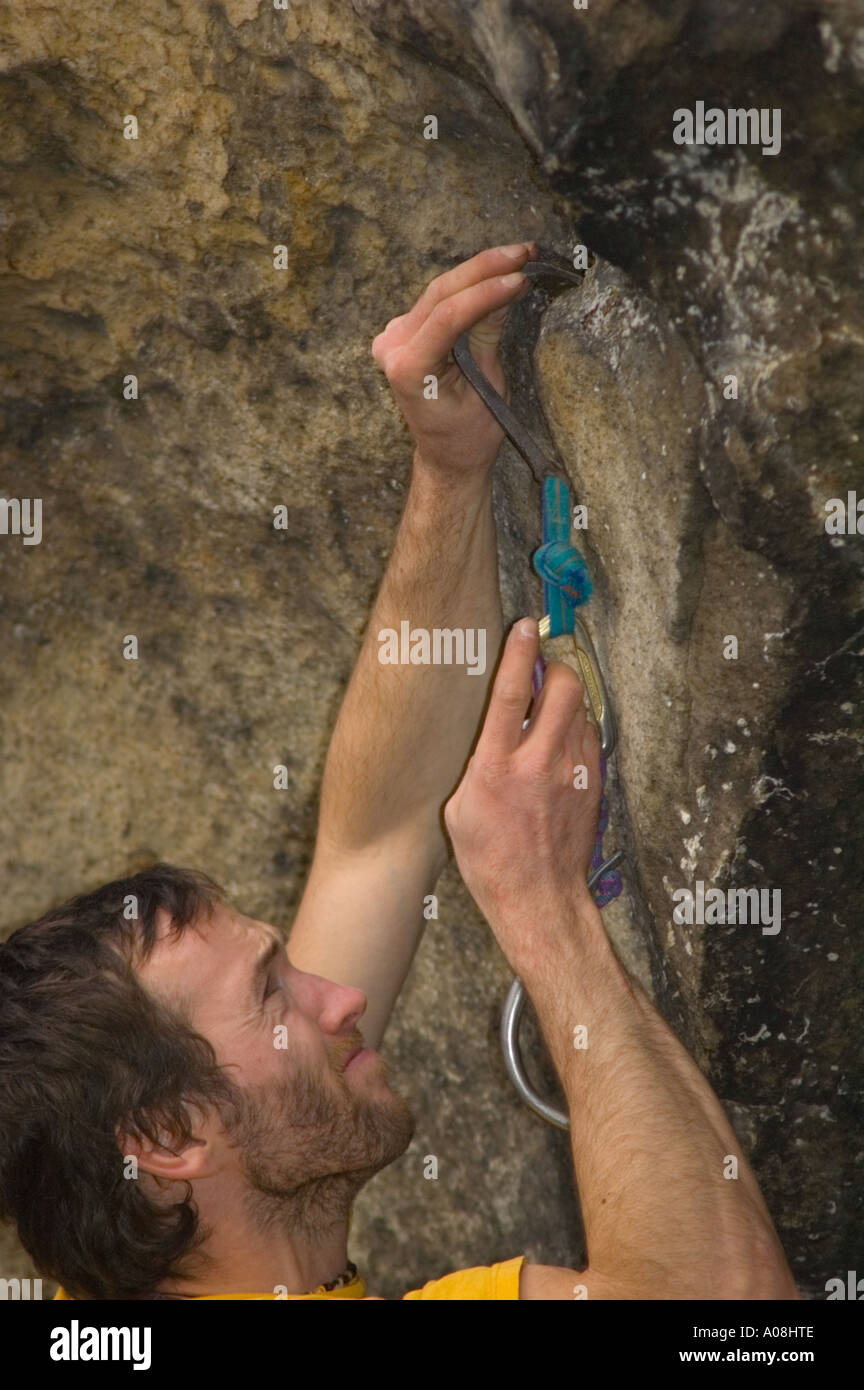 Climber placing a skyhook in order to be able to drill a bolt during  a ground up first ascent Stock Photo
