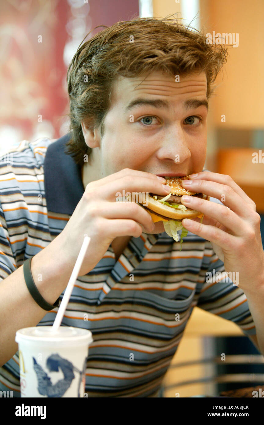 Junger Mann isst einen Hamburger, Young man eating hamburger Stock Photo
