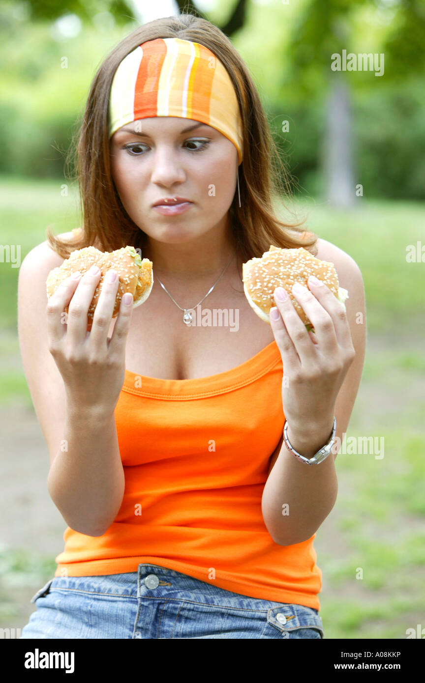 Junge Frau isst zwei Hamburger, Young Woman Eating Two Hamburgers Stock Photo