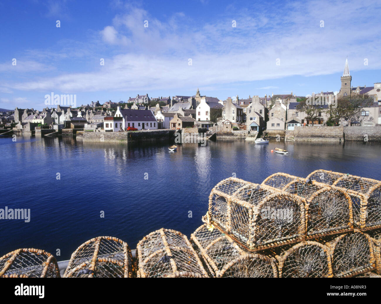 dh Scottish harbor waterfront STROMNESS HARBOUR ORKNEY Lobster creels scene quayside houses town fishing pots fish cages Scotland fishery Stock Photo