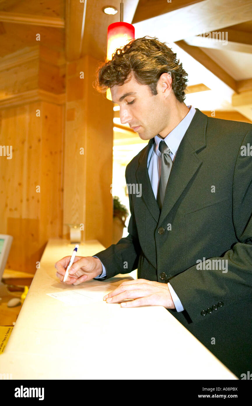 Mann beim Einchecken Bezahlen an der Hotelrezeption, Man checking out paying at the reception desk Stock Photo